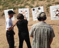 0801 NWS WellArmed2.jpg Clay Cross (left) and Dave Blake (right) assist Debi Friedly of Brighton with her position during shooting practice at a meeting of The Well Armed Woman Northern Colorado Chapter.